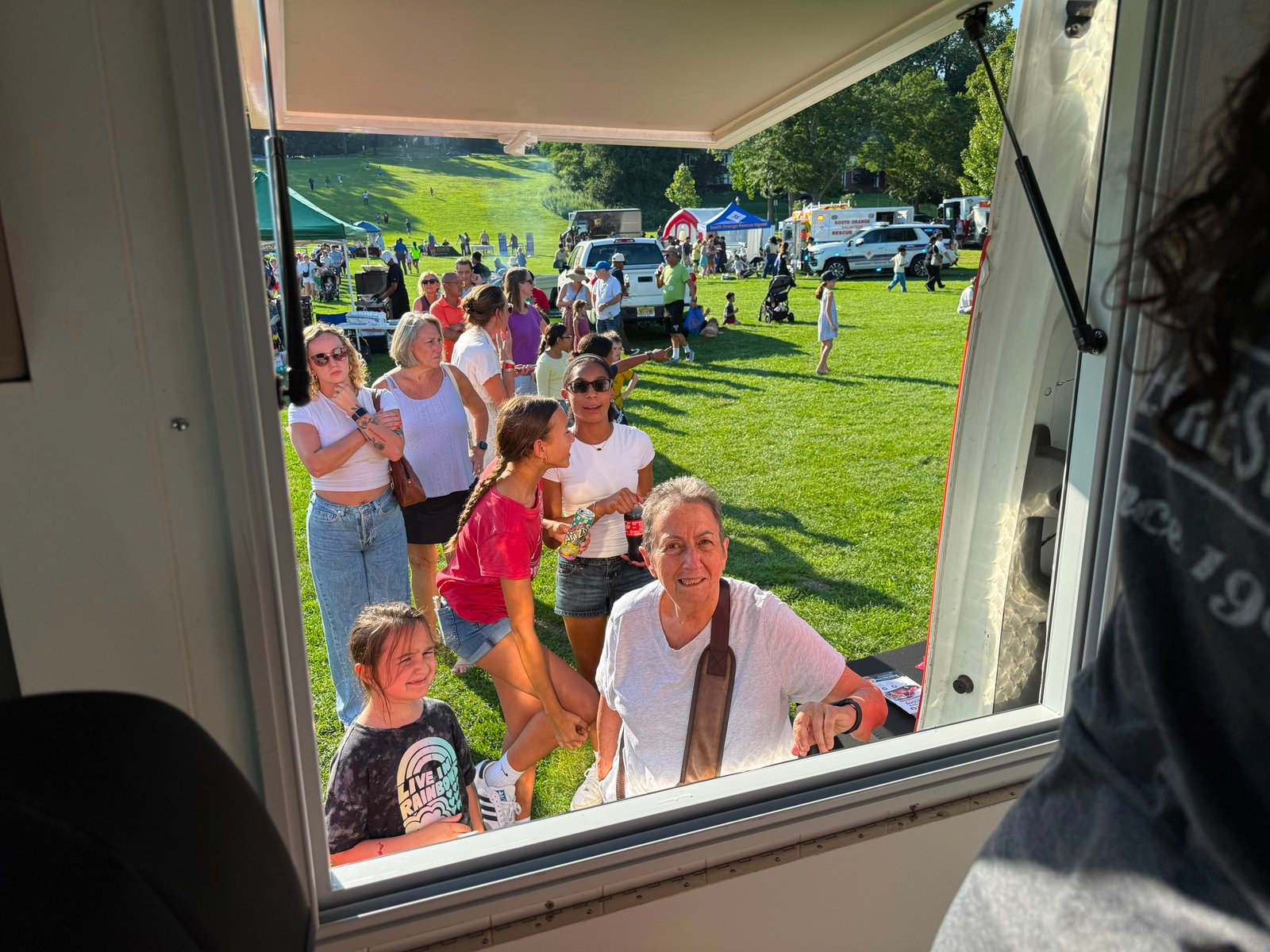 Guests smiling at the Cold Stone ice cream truck’s serving window during an outdoor event